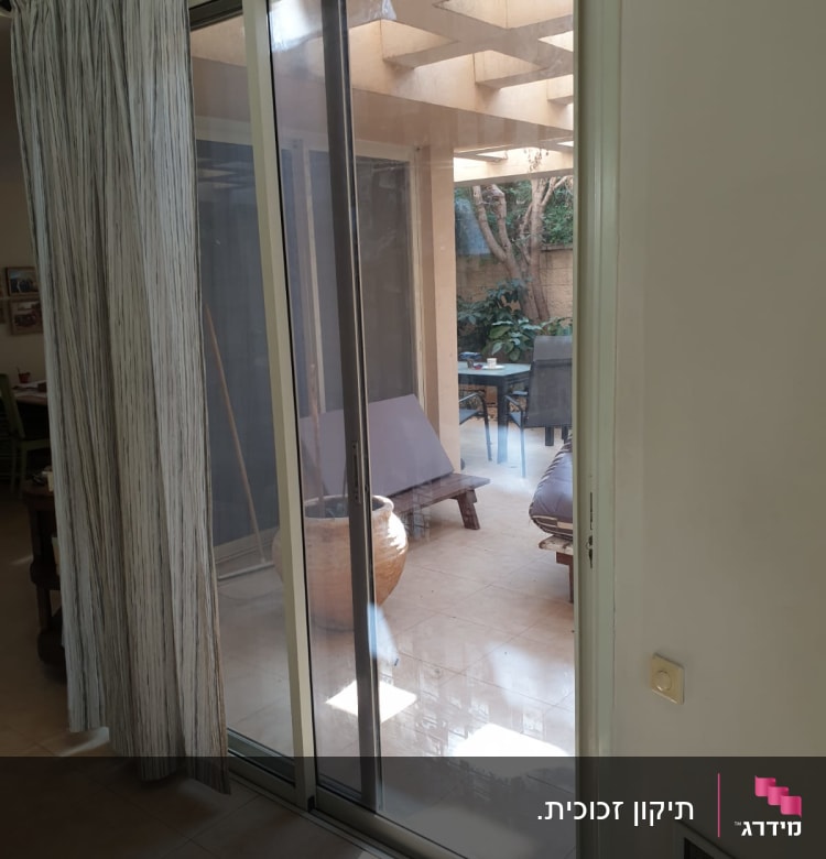 דלת זכוכית הזזה עם וילון בצד ימין